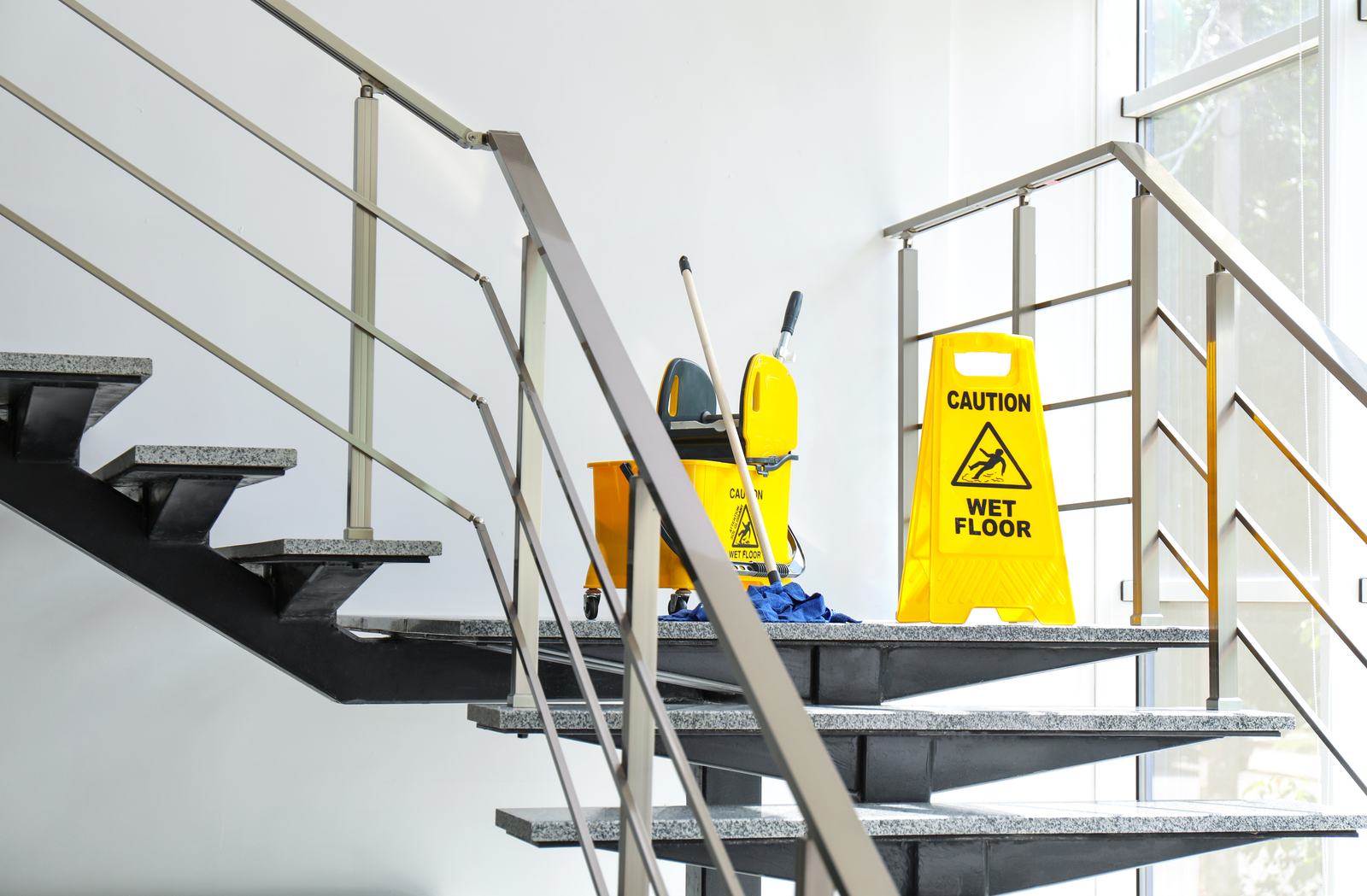 Wet-floor caution sign posted beside a mop bucket